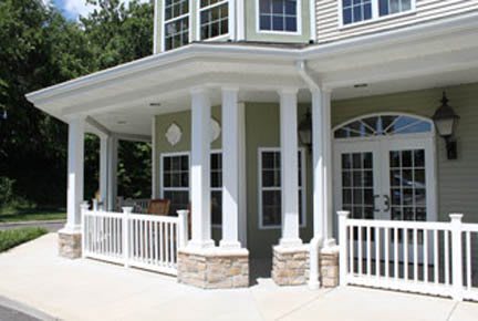 A modern house with a porch featuring white columns and railings.