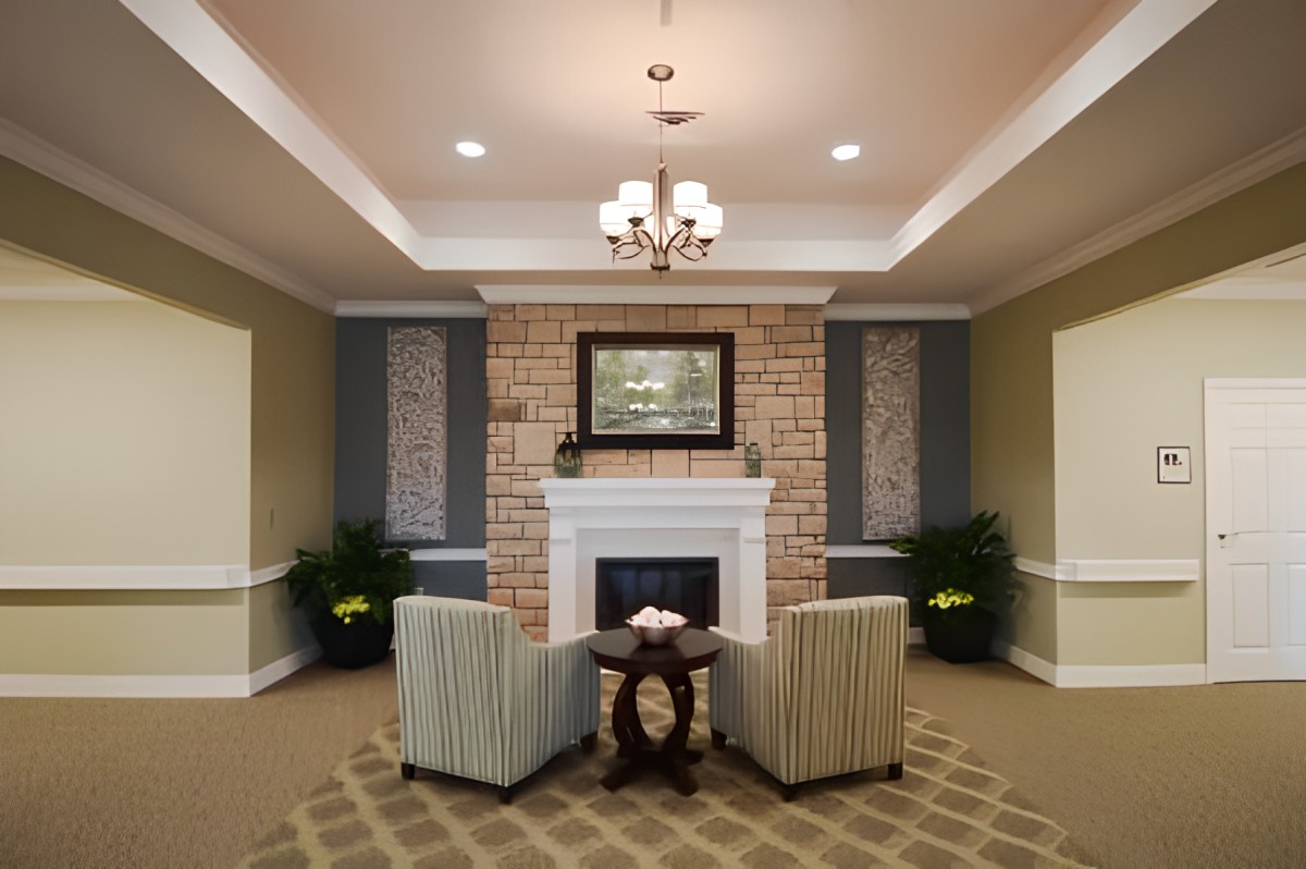 A cozy living room with a fireplace, two chairs, and elegant decor.