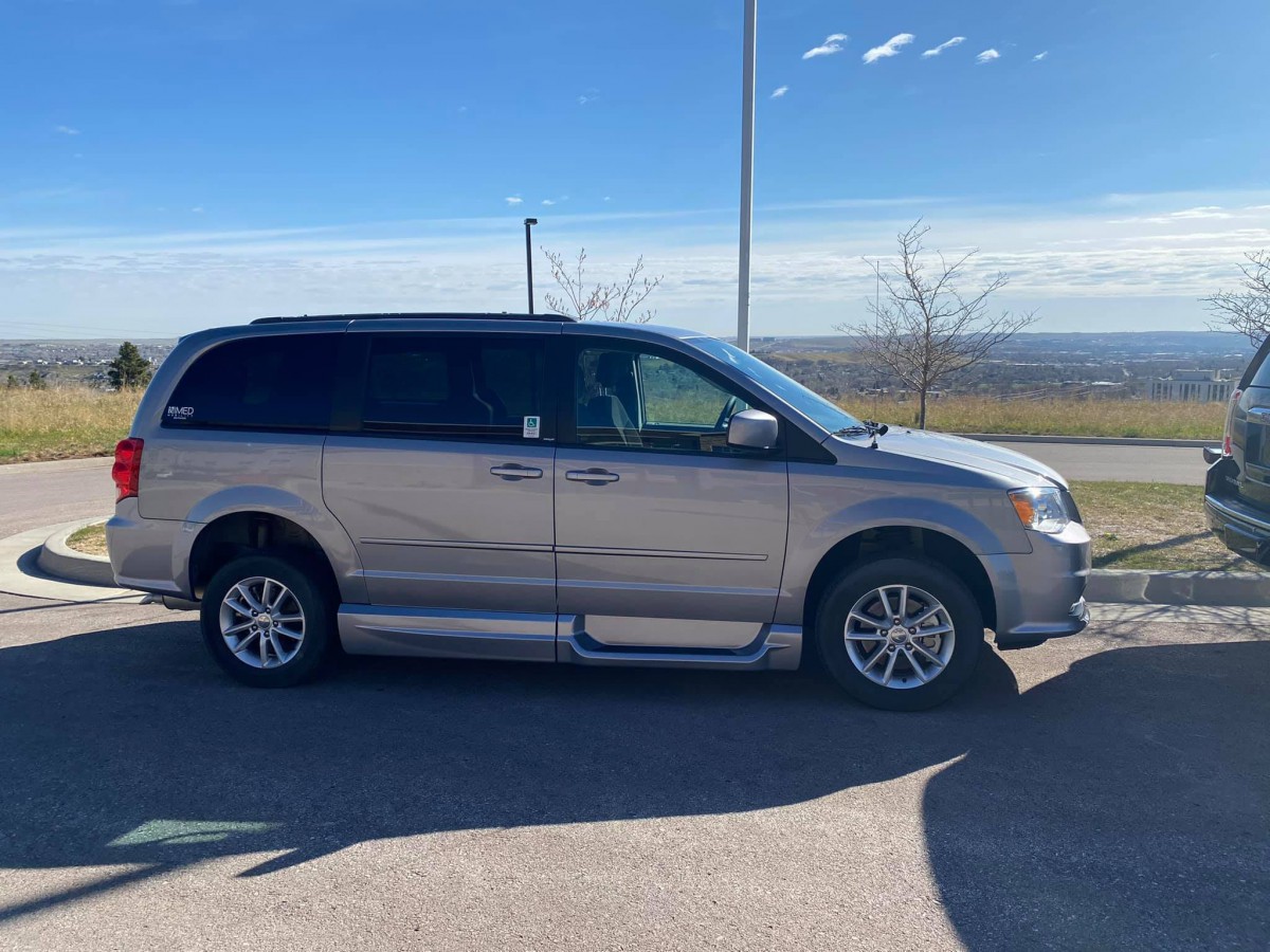 A silver minivan parked in a sunny parking lot.