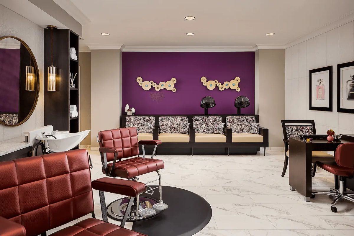 Modern salon interior with red chairs, a purple accent wall, and a stylish waiting area.