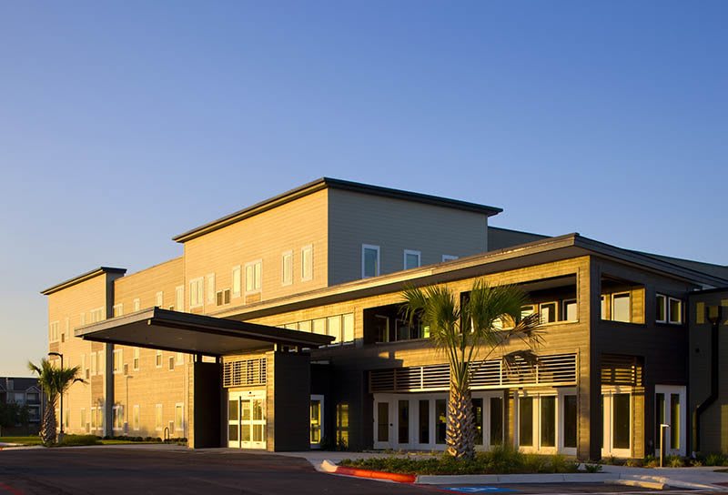 A modern commercial building with a prominent entrance under clear skies.
