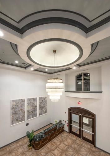 A modern lobby with a large chandelier and elegant ceiling design.