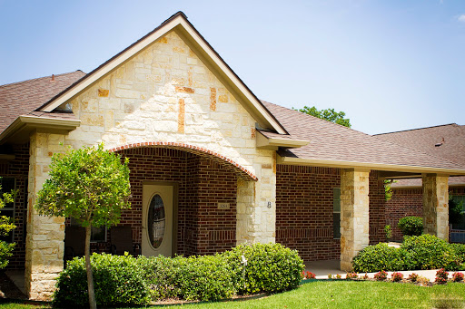 A charming residential house with a blend of brick and stone architecture, featuring well-maintained landscaping.
