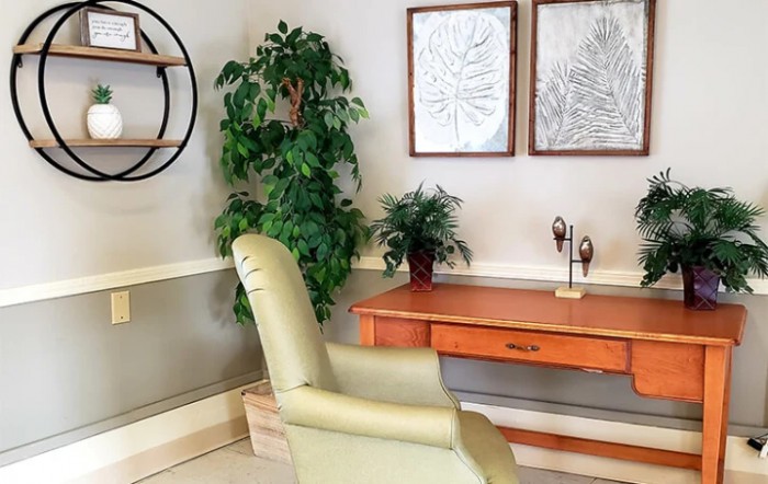 A cozy office corner featuring a desk, chair, indoor plants, and framed wall art.