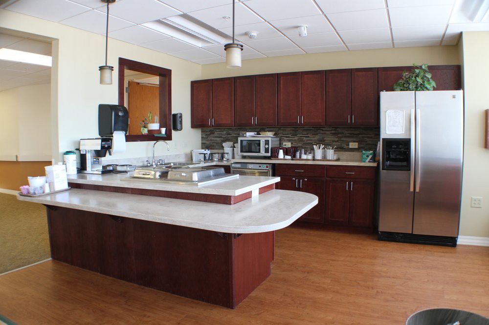 A modern kitchen with wooden cabinets, a central island, and various appliances.