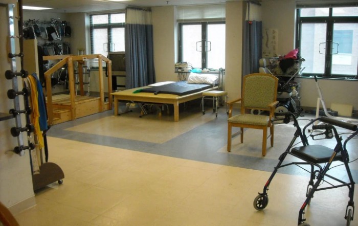 A rehabilitation room equipped for physical therapy sessions, featuring exercise equipment and seating.