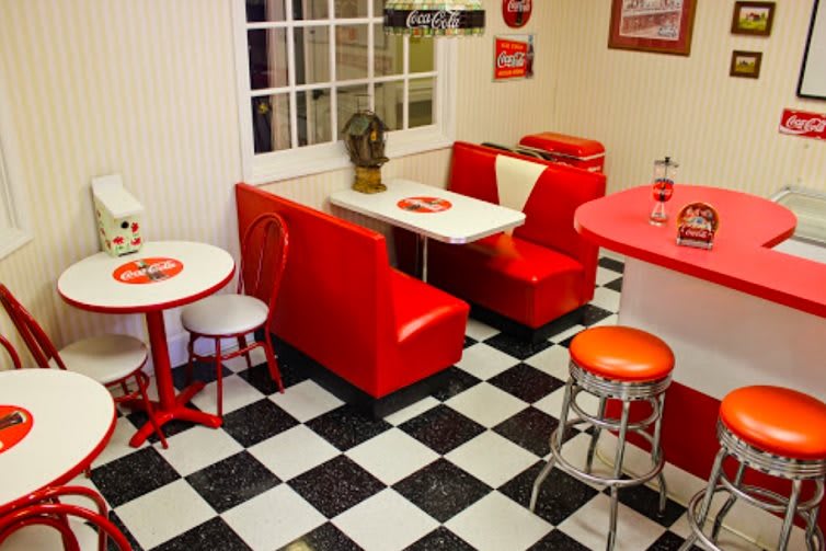 A retro-style diner with red booth seating and a classic black-and-white checkered floor.