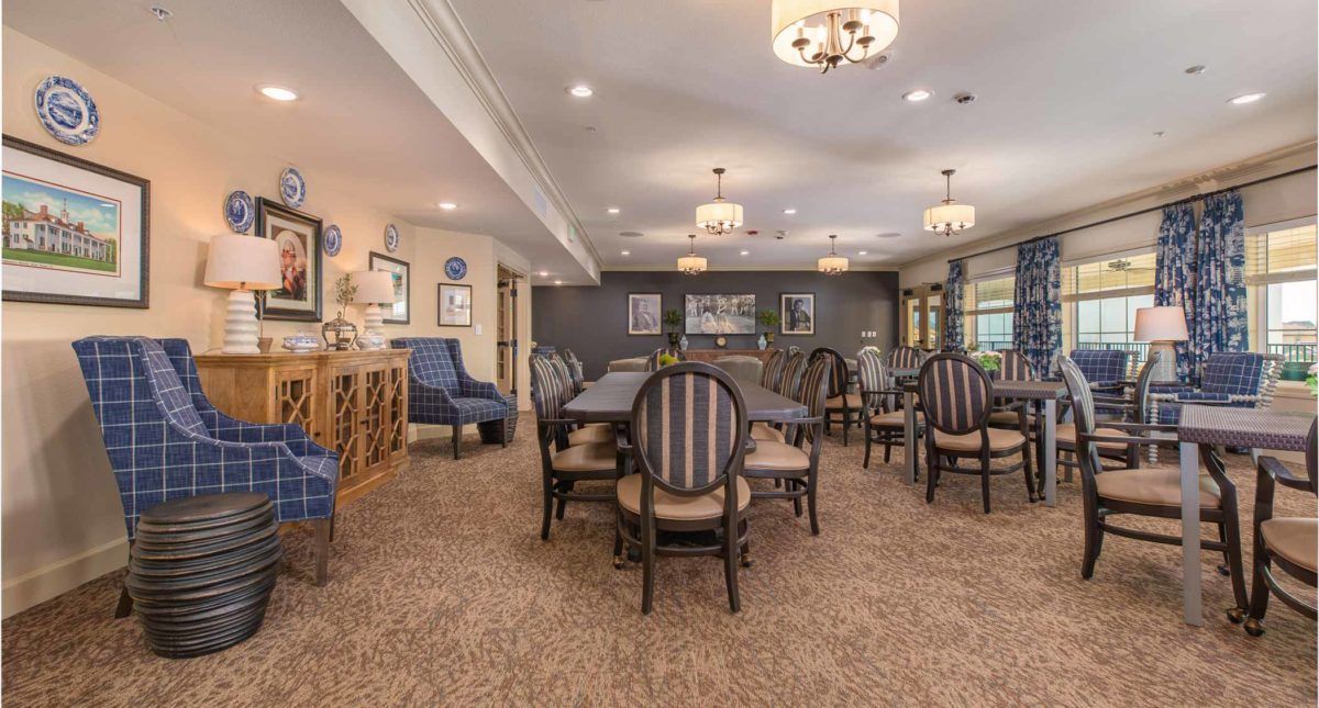 An elegantly designed dining room with multiple tables and chairs, featuring stylish lighting and decor.