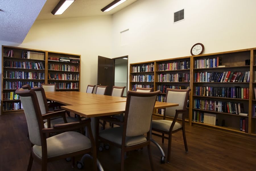 A well-organized meeting room with bookshelves, a large table, and multiple chairs.
