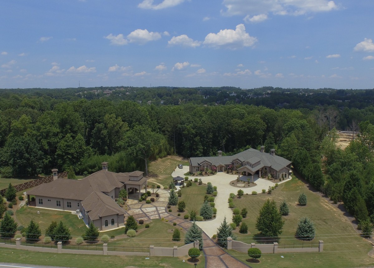 Aerial view of a large mansion surrounded by trees and landscaped grounds.