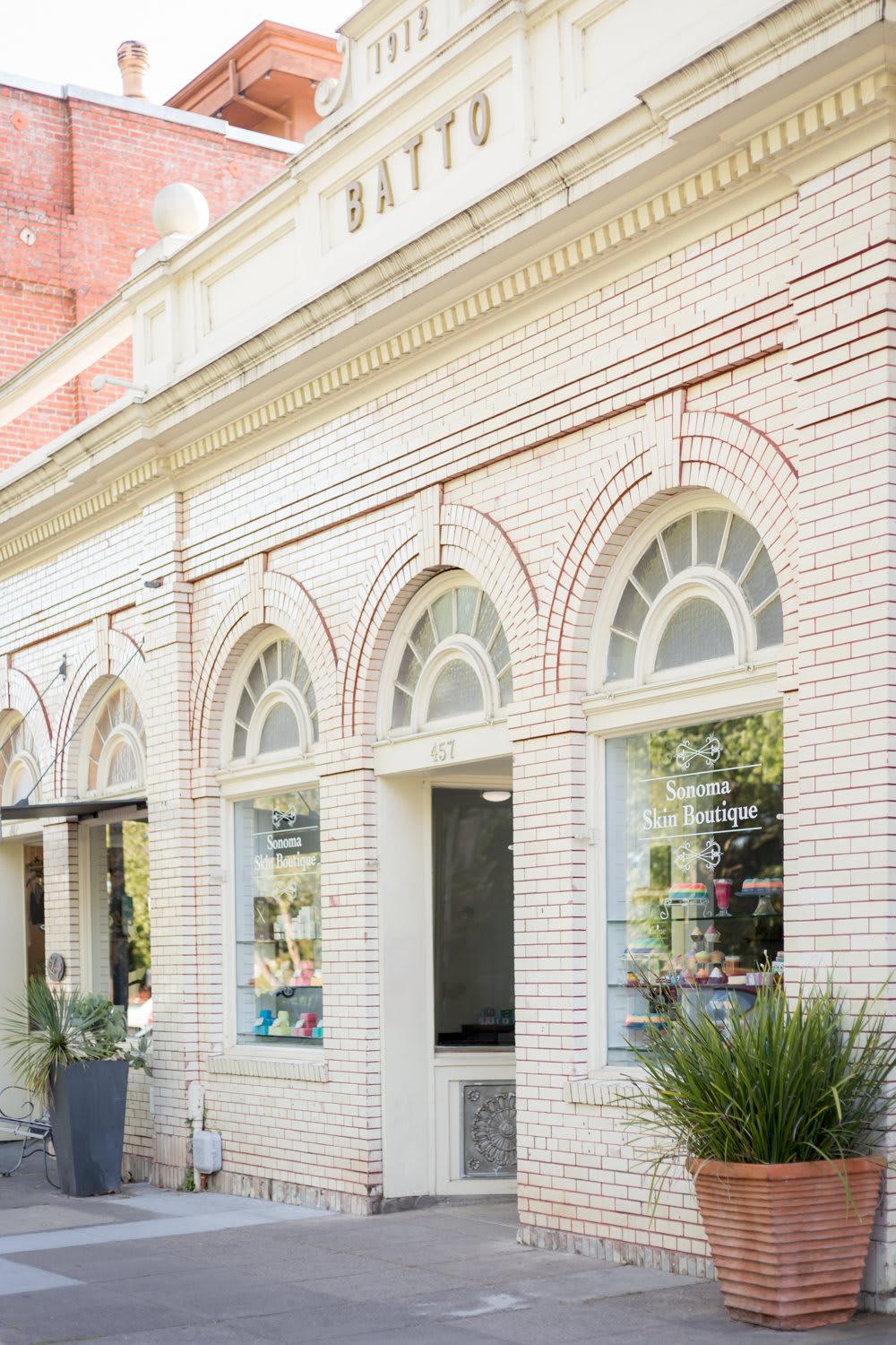 A charming brick storefront with arched windows on a sunny day.