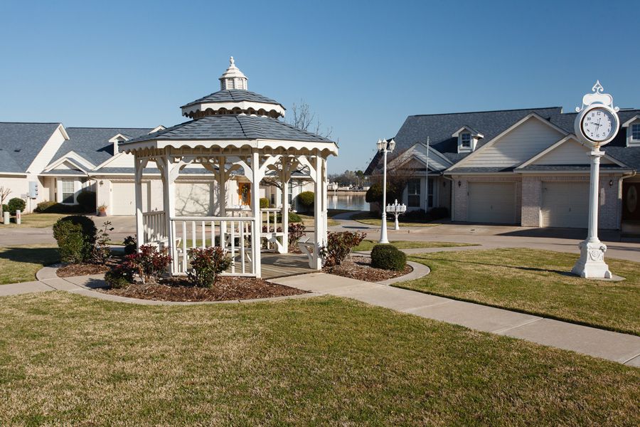 A suburban neighborhood with a white gazebo and houses in the background.
