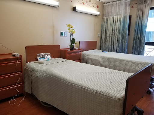 A view of a hospital patient room with two beds and calming decor.