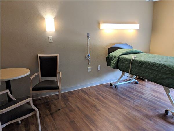 A modern hospital room with a bed, chair, and medical equipment.