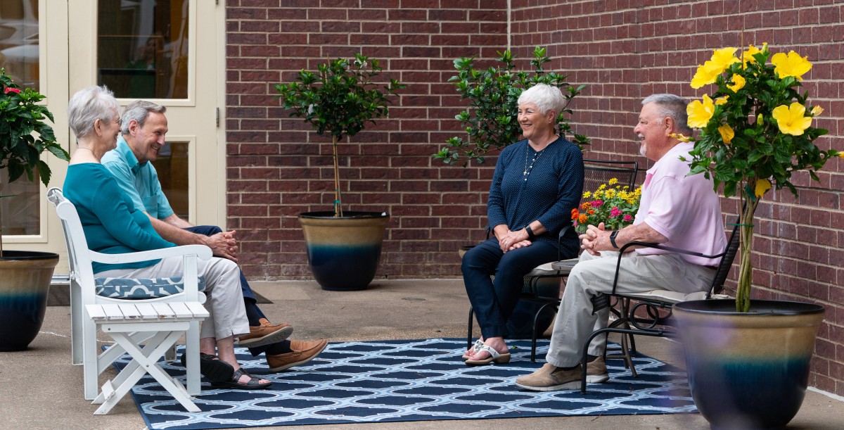 A group of people sitting outdoors having a conversation.
