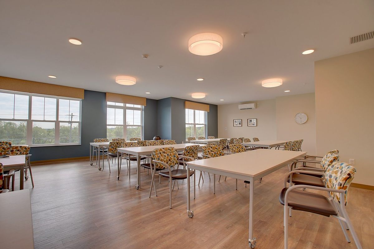 A spacious conference room with tables and chairs, featuring large windows and modern light fixtures.