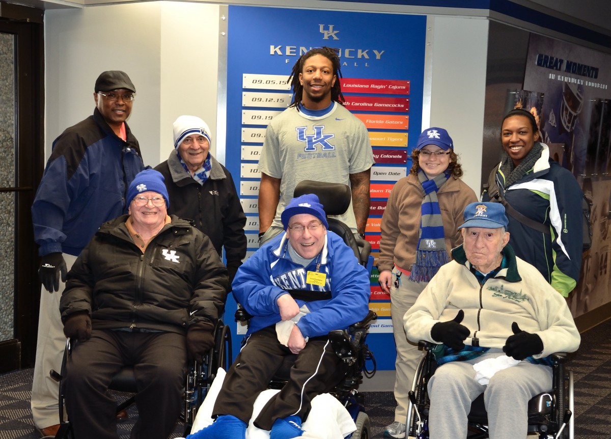 A group of people, some in wheelchairs, pose together indoors in sports attire.