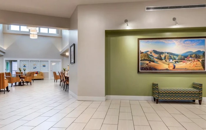 A spacious lobby with tiled flooring, featuring a seating area and a large framed artwork on a green accent wall.