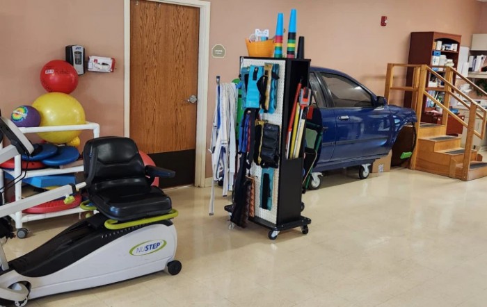 A janitorial setup with a floor scrubber and cleaning tools beside a car in an indoor space.