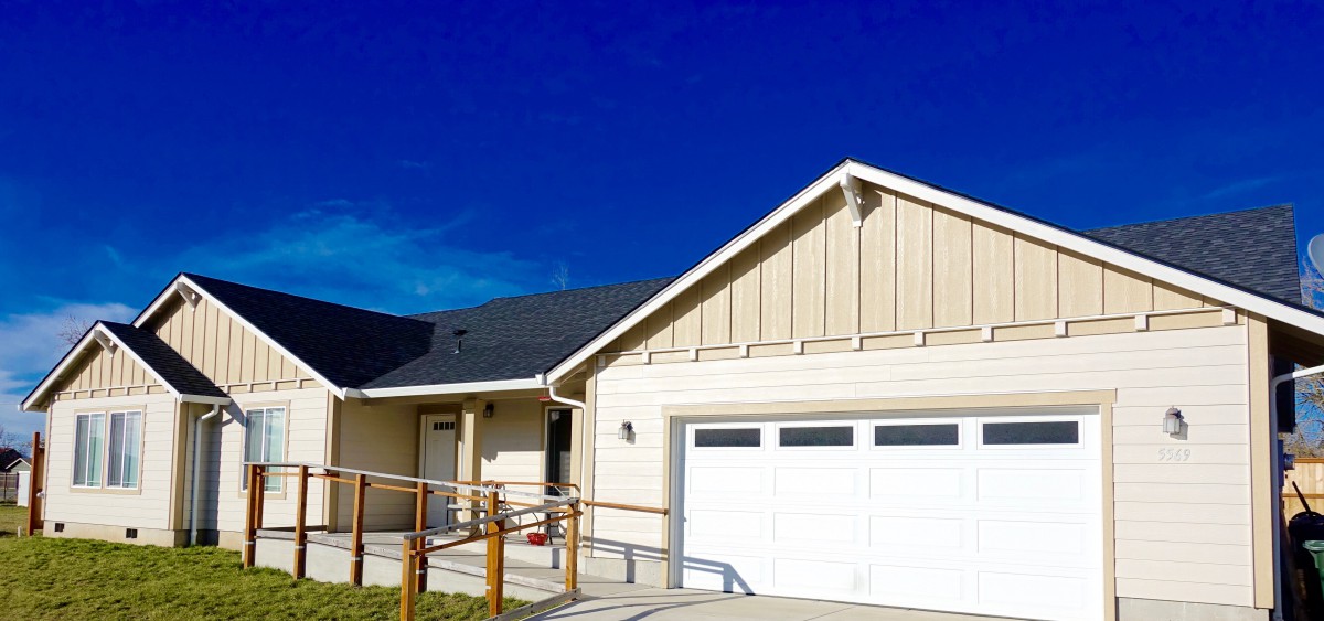 A modern house with a garage and sloped driveway under a clear blue sky.