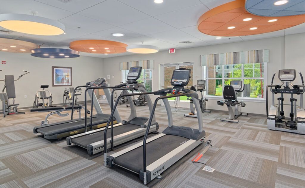 A modern gym with treadmills and elliptical machines.
