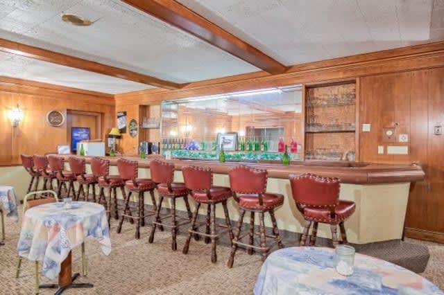 An interior view of a bar with multiple red stools lined up along the counter.