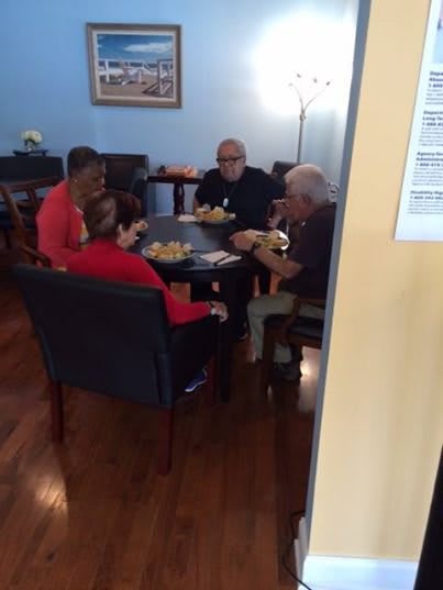 A group of people sitting around a table, enjoying a meal together indoors.