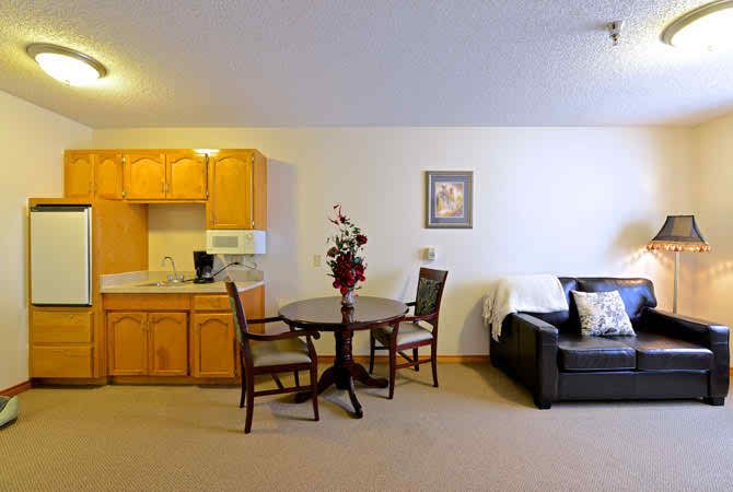 A cozy living space featuring a sofa, a small dining table with chairs, and a kitchenette.
