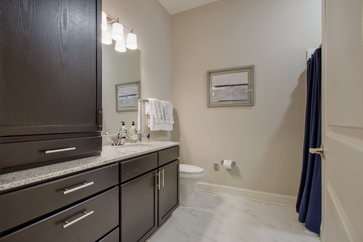 A modern bathroom featuring dark cabinetry, a large mirror, and stylish lighting.