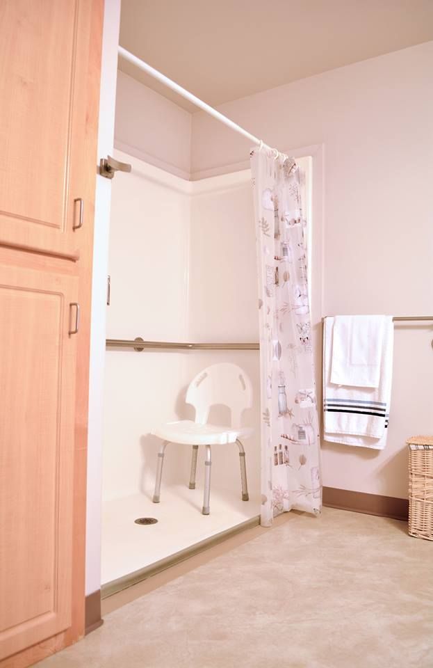 An accessible bathroom equipped with a shower chair and grab bars for safety.