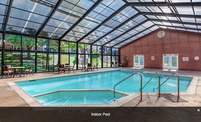 A modern indoor swimming pool with a glass ceiling.