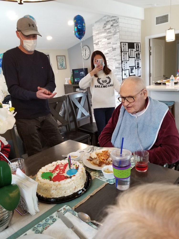 An elderly person celebrating their birthday with family around a table with cake.