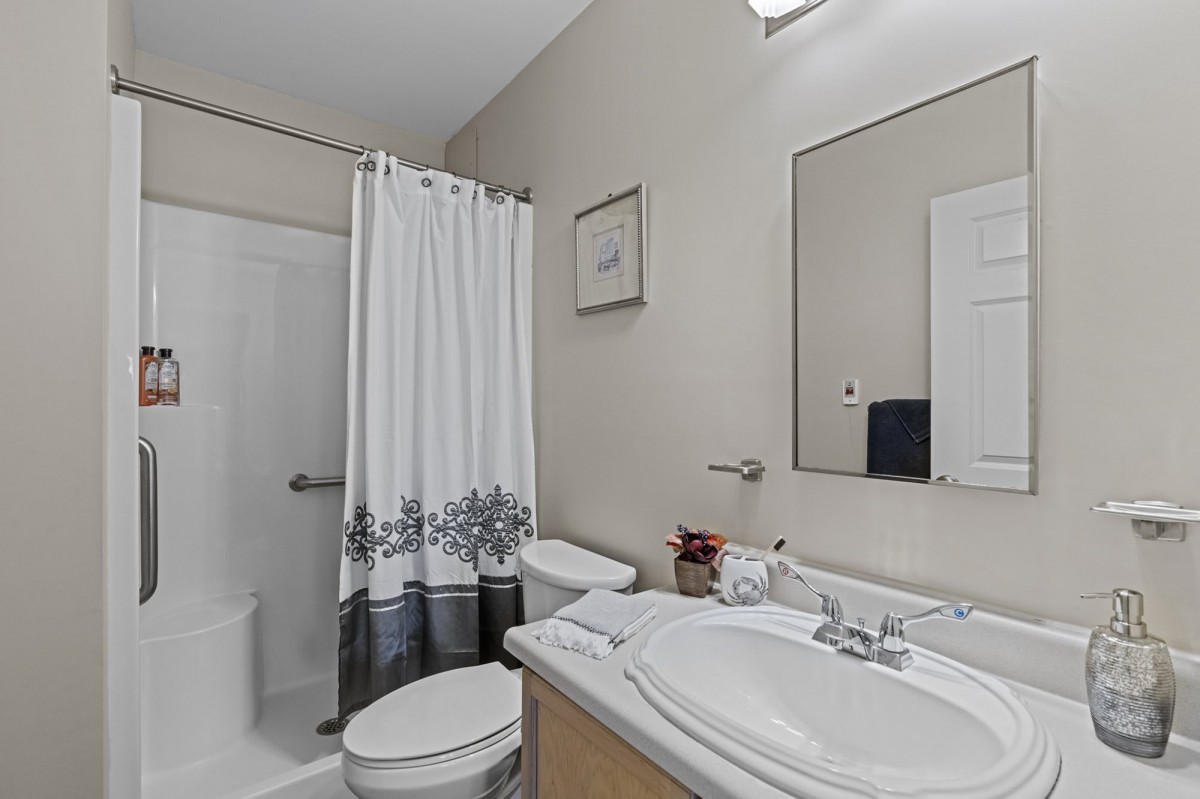 A clean and tidy bathroom with a shower, sink, and mirror.