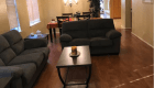 A cozy living room with a sofa and coffee table leading into a dining area.