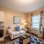 A cozy living room with a sofa, stylish decor, and ample natural light.