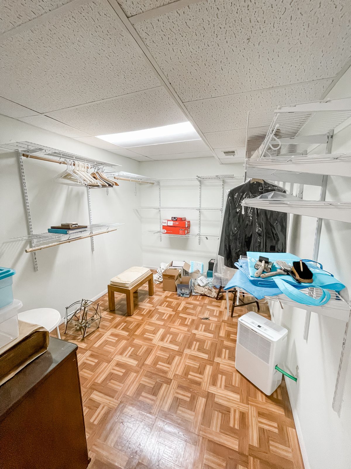 A small basement utility room with clothes hanging and various items stored on shelves.