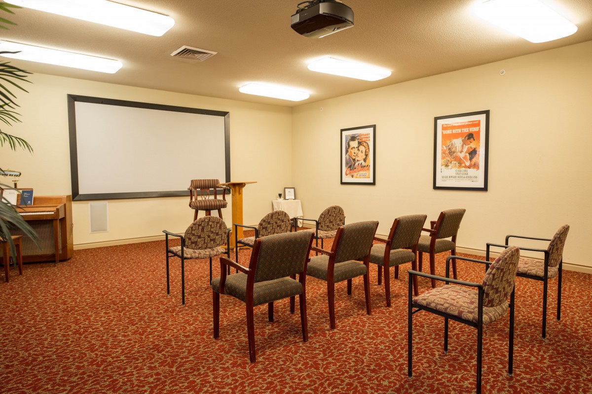 A small conference room setup with chairs facing a projector screen.