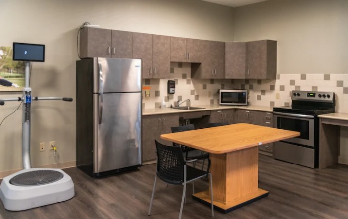 A modern kitchen interior with appliances and a central wooden table.