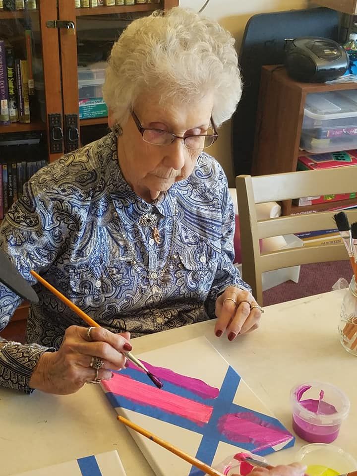 An elderly woman engaged in painting as a creative hobby.