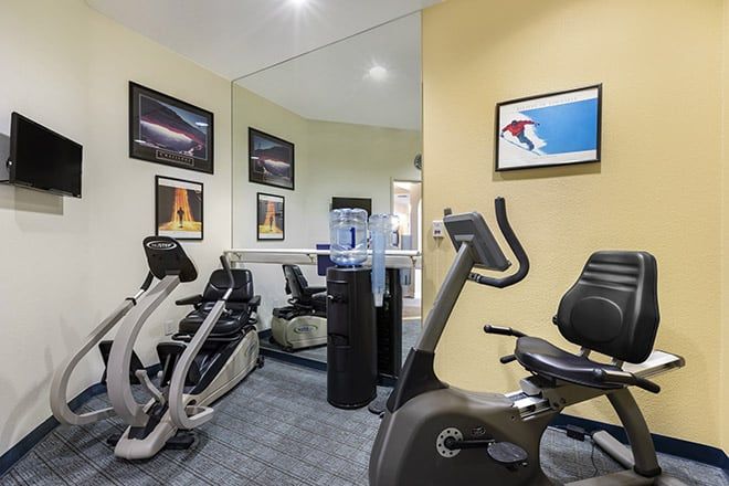 A well-equipped home gym featuring stationary bikes and an elliptical machine, with motivational posters adorning the walls.
