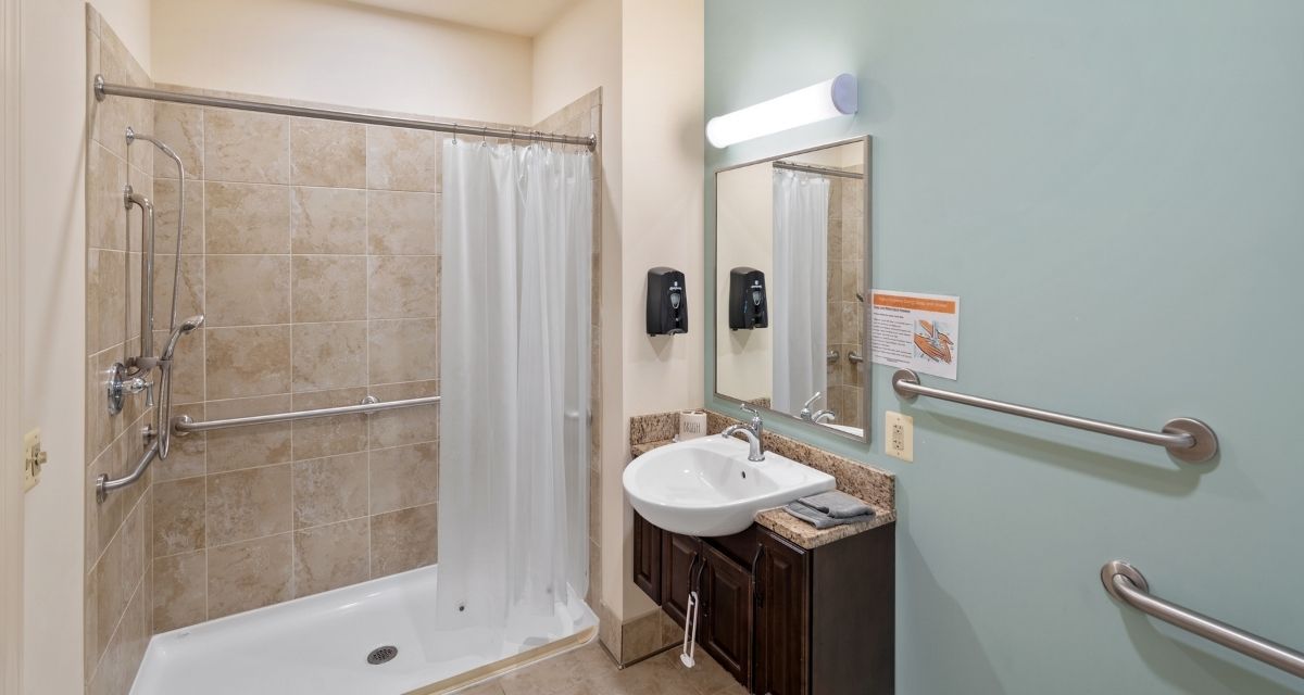 A clean and modern bathroom with a shower, sink, and mirror.