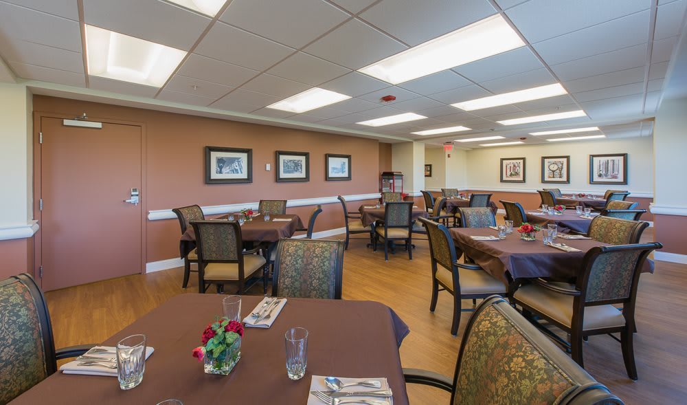 A well-lit dining area with neatly arranged tables and chairs, adorned with artwork on the walls.