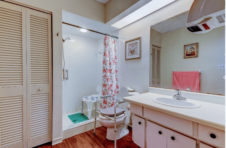 A cozy bathroom with a shower, sink, and toilet featuring floral decor.
