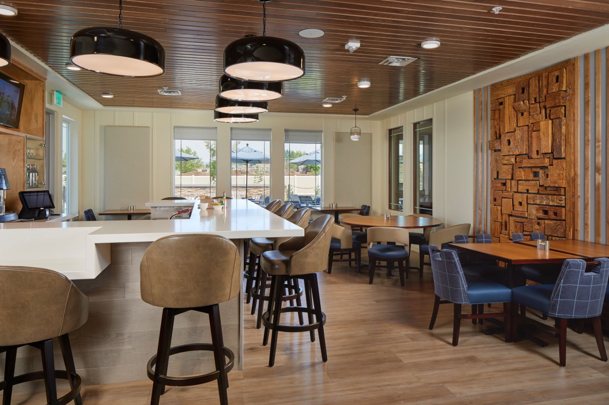 A modern restaurant interior featuring a spacious dining area with stylish seating and wooden decor.