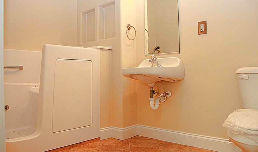 A bathroom with a wall-mounted sink and mirror, featuring a tiled floor.