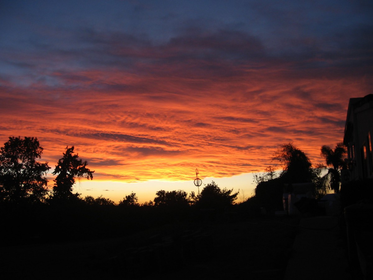 A vibrant sunset with orange and red clouds silhouetting the horizon.