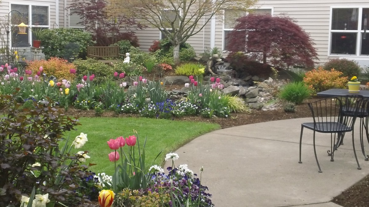 A beautifully landscaped garden with a variety of colorful flowers and plants surrounding a curved pathway.