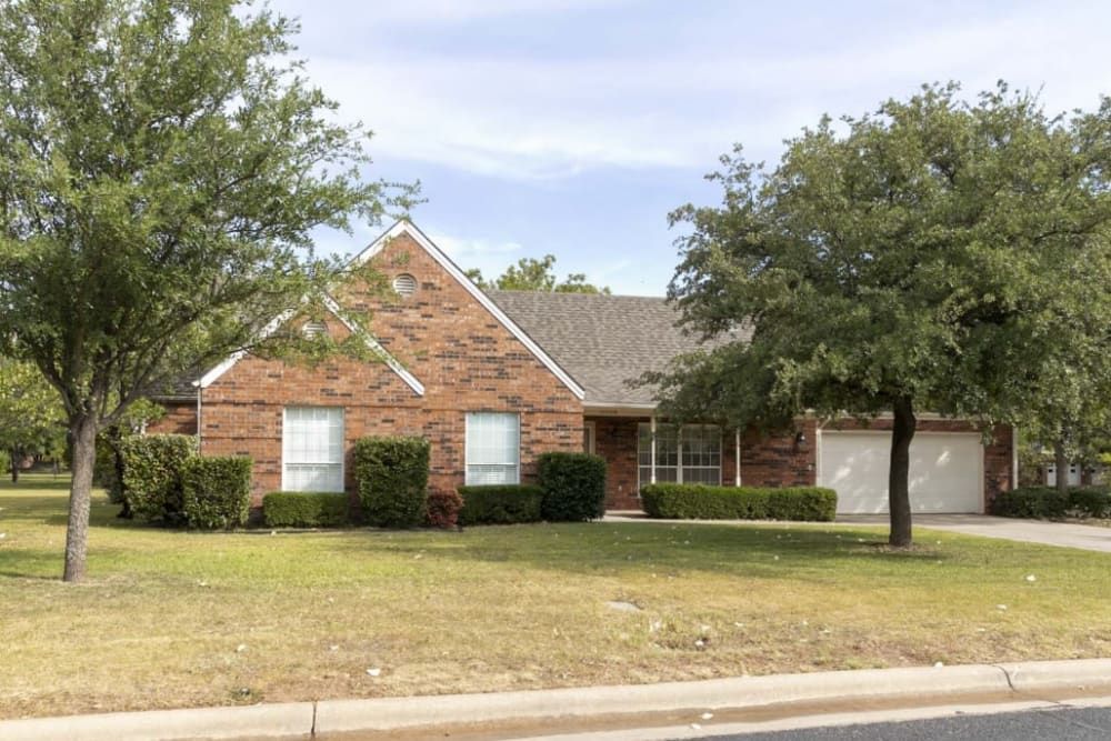 A brick house with a front yard in a suburban setting.