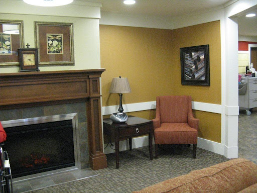 A cozy living room corner featuring an armchair, lamp, and a decorative fireplace.