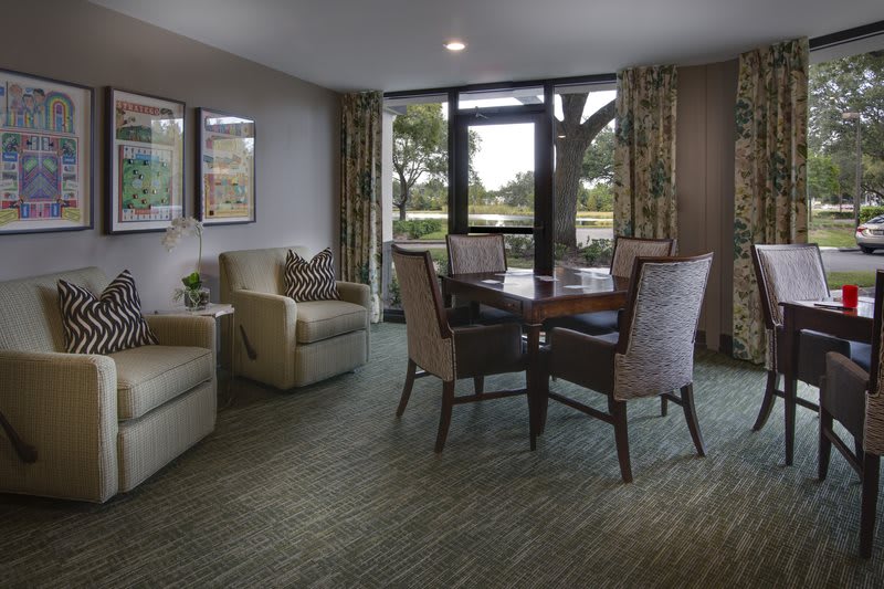 A cozy living room setup with a round table and comfortable chairs near large windows.